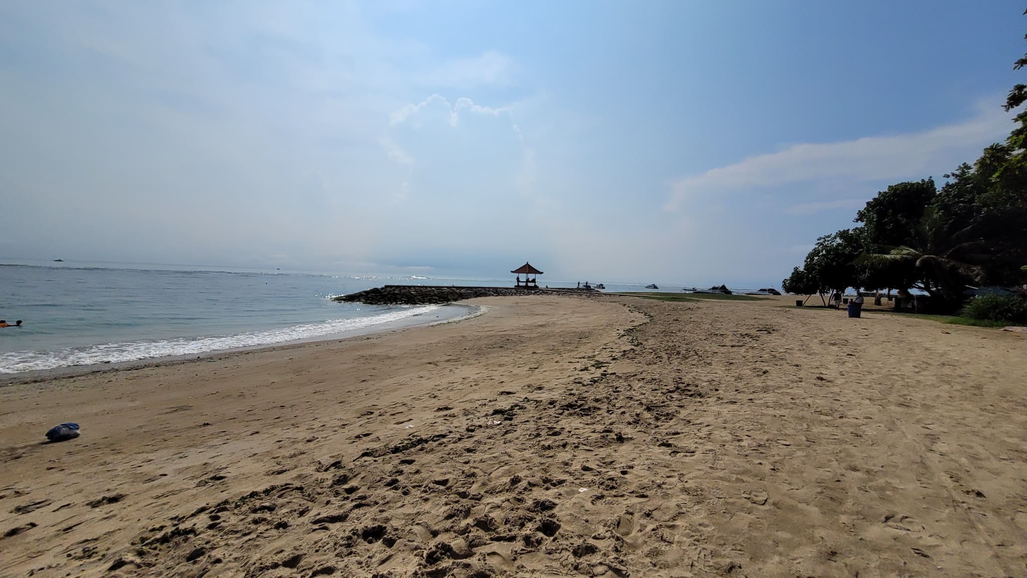 Het zandstrand van Sanur met de zee en een paviljoen op de golfbreker