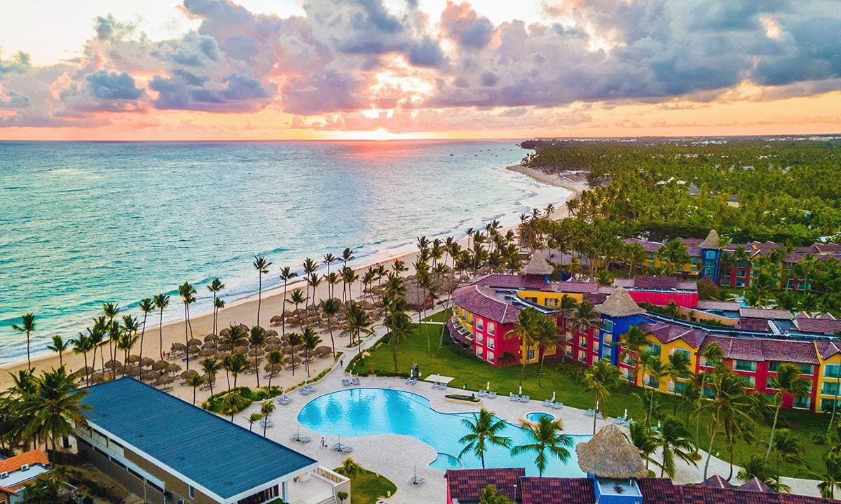 Vogelperspectief op Tropical Deluxe Princess met gekleurde gebouwen, zwembad en strand bij zonsondergang