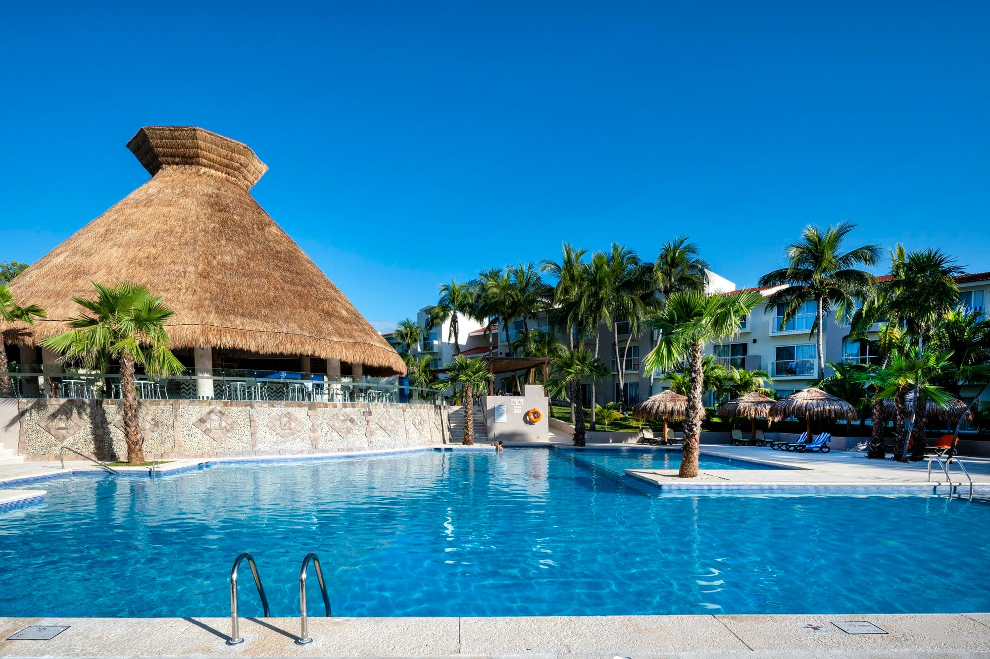 Zwembad met palmen en rieten paviljoen bij Viva Azteca